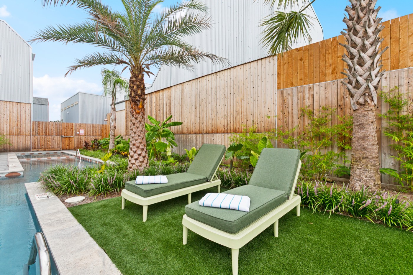 Loungers beside a private heated pool with palm trees at a New Orleans group villa
