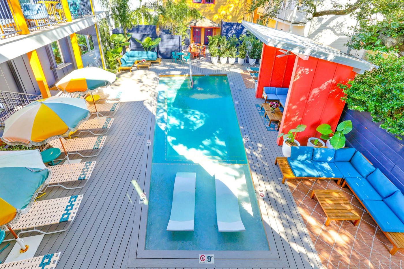 The Syd's colorful courtyard pool with umbrellas and loungers, seen from above